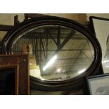 An Edwardian carved framed oval wall mirror.