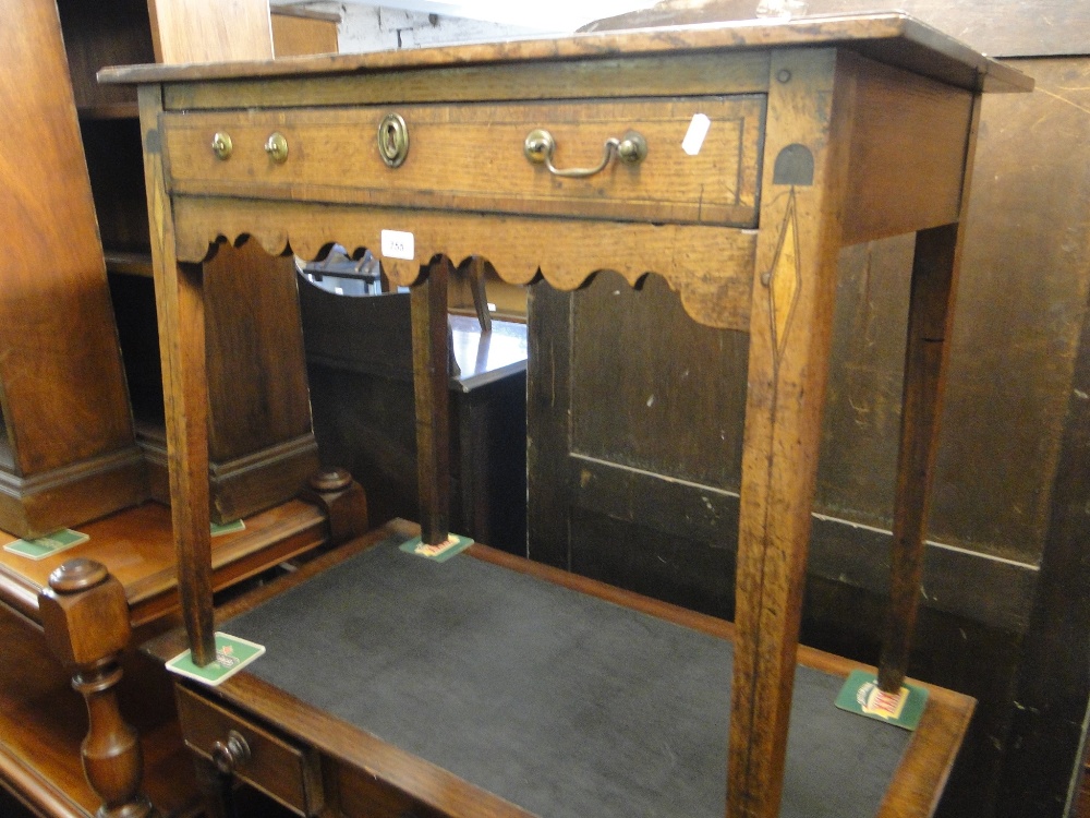 A Georgian oak low boy with single frieze drawer, shaped apron and square tapered legs.