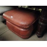 A tan leather upholstered footstool.