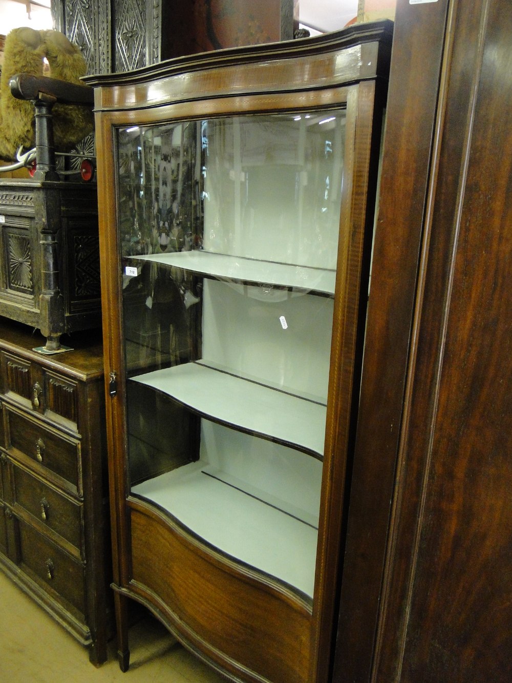 An Edwardian mahogany serpentine front glass display cabinet.