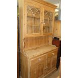 A modern polished pine dresser, the top having glazed doors with cupboards under.
