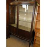 An Edwardian mahogany bow front display cabinet with 2 glazed and panelled doors raised on shell
