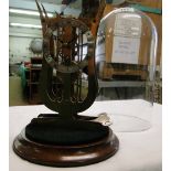 A skeleton clock under glass dome on plinth.