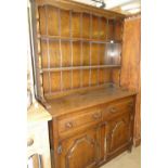 A reproduction Ipswich oak dresser, with boarded open plate rack and drawer and cupboards under,