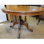A Victorian mahogany oval tilt top loo table on a carved quadruple sabre leg base.