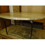 An oval marble top coffee table on tapered brass legs.