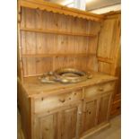 A polished pine dresser with open plate rack and drawers and cupboards to the base.