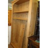 A large floor standing polished pine open bookcase with adjustable shelves.