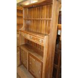 An oak cabinet, with open shelves drawers and cupboards.