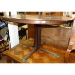 A Danish rosewood extending circular dining table on shaped base with 2 spare leaves,
