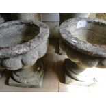 Pair of weathered concrete garden planters on stands.