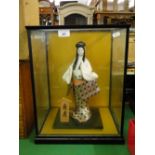 A Japanese porcelain doll in glazed display case.