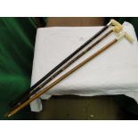 A walking cane with carved bone handle, a silver collared walking cane and another.