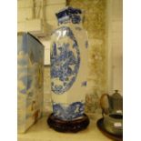 A tall blue and white Chinese vase on carved wood stand.