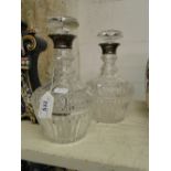 A pair of cut-glass decanters and stoppers with silver collars.