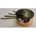 A graduated set of 5 copper saucepans with brass handles.