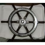 A turned wood ships wheel with plated mounts.