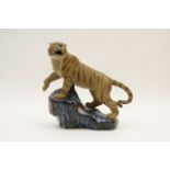 Pottery model of a tiger, modelled growling, on a blue glazed rock, 20th Century,