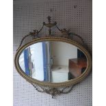 A neo-classical gilt mirror, oval-shape with urn and phoenix cresting, bevelled plate, 2ft. 9in.