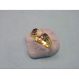 A yellow metal ring, claw-set with central opal and two amethysts, size K/L