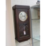 A 1930's dark oak hall clock, silvered dial and gong-striking movement, 30in. high