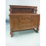 A solid, dark oak sideboard, panelled cupboard base with carved detail and three drawers, grape