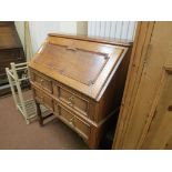 A 1920's solid, medium oak bureau, fall-front above two long drawers, panelled in Jacobean style,