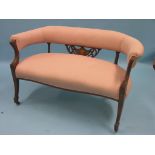 An Edwardian two-seater settee, inlaid mahogany frame upholstered in a pink brocade, on casters