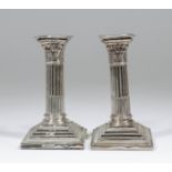 A pair of Edward VII silver pillar candlesticks with cast Corinthian capitols and stop fluted