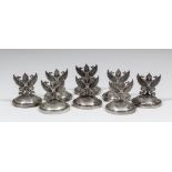 A set of eight Siamese silvery metal menu holders cast with winged mythical figure on loaded
