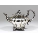 A William IV silver teapot with squat lobed circular body, conforming lid with cast floral finial,