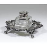 A Victorian silver rectangular inkstand of shaped outline with cast floral sprays and scroll mounts,