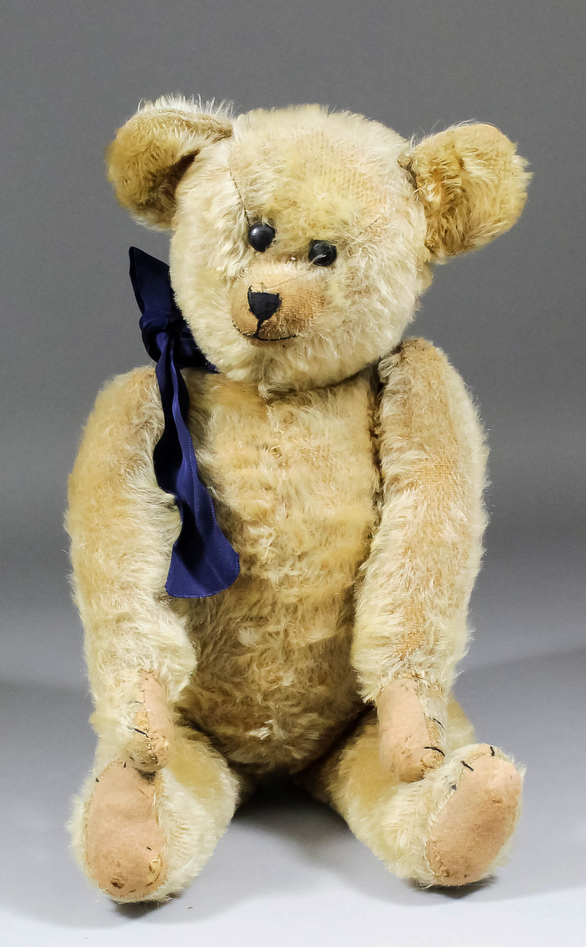 An early 20th Century American blond mohair teddy bear with black button eyes and hump, 21.25ins