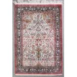 A good Qum silk prayer rug woven in colours with a central mihrab filled with vase of flowers and