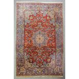 An Isfahan carpet woven in colours with a bold central medallion, palmettes and leaf scroll ornament