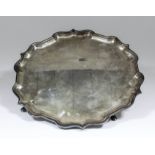 An Elizabeth II silver circular salver with shaped and moulded rim, on four scroll supports with pad