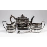 A George V silver oval four piece tea service, the reeded body engraved with band of trellis