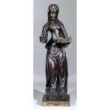 A late 16th Century carved oak figure of a female saint with open book in her left hand, her right