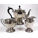 A George V silver circular tea service with shaped rim, panelled body, on circular footrims,