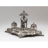 A late 19th Century French ovoid inkstand of shaped and moulded outline, the centre with cast seated