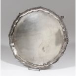 A George V silver circular salver of Georgian design, the moulded rim with gadroon mounts, on four