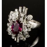 A modern 18k white gold ruby and diamond set flowerhead pattern ring, the central oval cut ruby