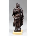 A 17th Century carved fruitwood figure of a standing Saint, his right hand pressed against his