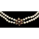 A modern 9ct gold and cultured pearl two strand necklace with garnet and pearl set flowerhead