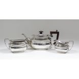 A George V silver rectangular three piece tea service of plain panelled form with angular loop