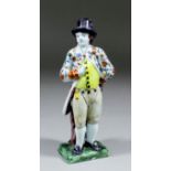 A 19th Century Dutch Delft polychrome figure of a standing gentleman with top hat and yellow