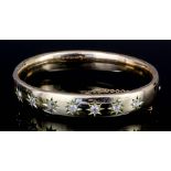 A late Victorian gold coloured metal diamond set stiff pattern bangle, the face "Gypsy" set with