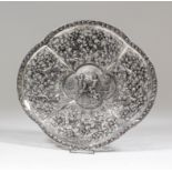 A Continental silvery metal oval dish of shaped outline, the rim cast with fruit and leaf