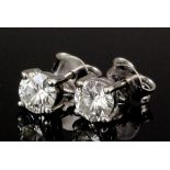A pair of silvery coloured metal mounted diamond solitaire earrings (for pierced ears) the brilliant