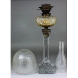 A Victorian oil lamp on plain glass stepped column with plated Corinthian capitol supporting a cut-